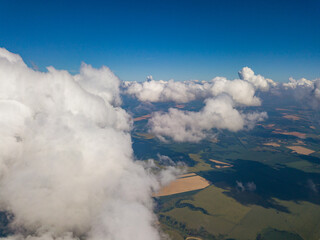 Obraz premium High flight in the clouds over agricultural fields in summer.