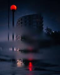 Reflection of urban buildings in a puddle of rain water at night