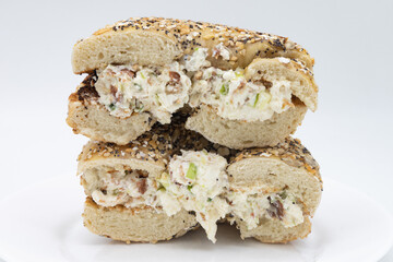 Cut in Half Everything Bagel with Bacon Scallion Cream Cheese on a White Plate and a White Background