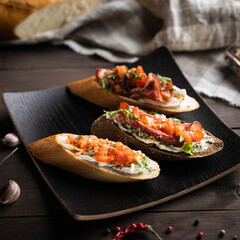 From above yummy bruschettas placed on square plate near napkin and spices in kitchen