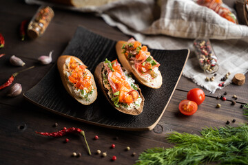From above aromatic spices and vegetables placed near plate with yummy sandwiches on wooden table