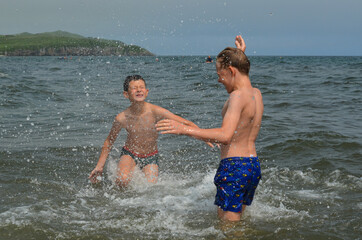 Caucasian children in the sea on the beach in summer