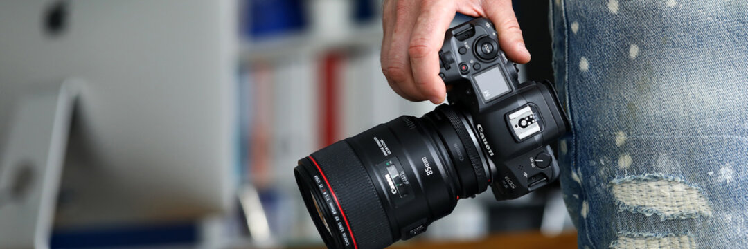 Male hand holding brand new mirrorless digital camera Canon r5 closeup