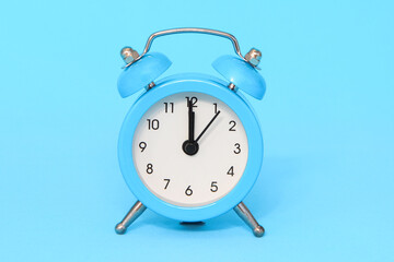 Blue alarm clock on blue background close up.12 a.m., 12 p.m. Time concept.