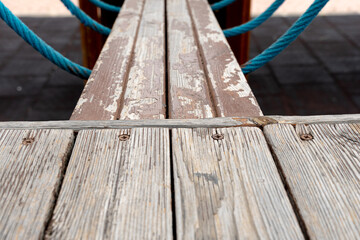 rowing boy catwalk in wooden playground with blue ropes worn by time