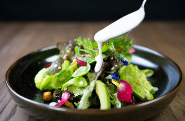 Fresh and green vegetables in a brown ceramic bowl, in low lighting atmosphere.