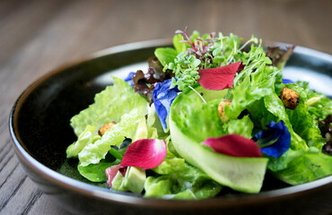 Fresh and green vegetables in a brown ceramic bowl, in low lighting atmosphere.