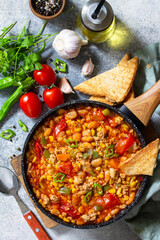 Traditional mexican food. Chili con carne from meat, beans and vegetables on dark stone table. Top view flat lay background.