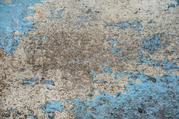 A dirty and worn textured concrete background, partially painted with blue paint, with a lot of depressions and scratches.