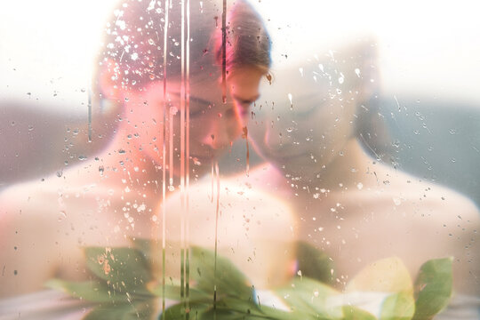 Nature portrait. Nostalgic melancholy. Sensual peaceful woman face blur silhouette with green leaves behind steamed wet glass double exposure effect. Freshness purity. Feminine beauty.