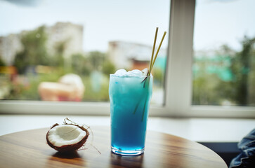 Blue hawaii cocktail and coconut on table in bar.Blurred image,selective focus