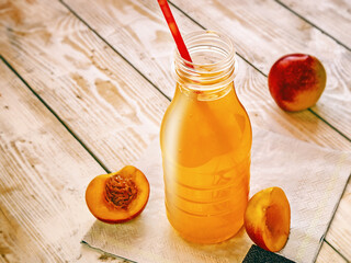 fruit non-alcoholic drink in a bottle with pieces of nectarine fruit on a wooden background
