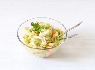 Fresh cabbage and carrot salad with parsley in a bowl on a white background