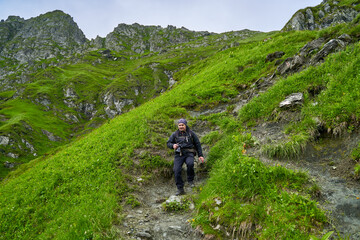Fototapeta premium Hiker man with backpack on a mountain trail