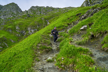 Fototapeta premium Hiker man with backpack on a mountain trail