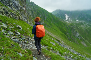 Naklejka na ściany i meble Lady hiker on a trail in the mountains