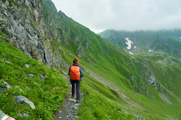 Naklejka premium Lady hiker on a trail in the mountains