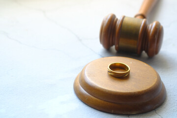 Divorce concept with gavel and wedding rings on table.