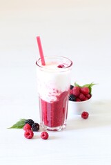 Milk berry refreshing drink, cocktail with ice cream, fresh raspberries and blackberries in a glass on a white background