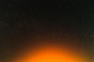 Night sky with golden glow from below village.