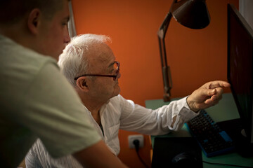 the grandson educates the grandfather on the computer