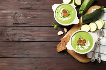 Tasty homemade zucchini cream soup served on wooden table, flat lay. Space for text