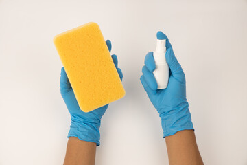 Sponge and spray for cleaning in female hand. Hand in a latex glove isolated on white. A hand in a glove holds a sponge and spray  cleaning.