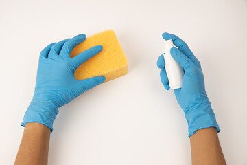 Sponge and spray for cleaning in female hand. Hand in a latex glove isolated on white. A hand in a glove holds a sponge and spray  cleaning.