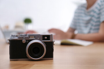Woman planning trip at wooden table, focus on vintage camera