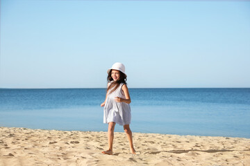 Cute little child running at sandy beach on sunny day