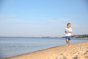 Fototapeta na wymiar Cute little child running at sandy beach on sunny day