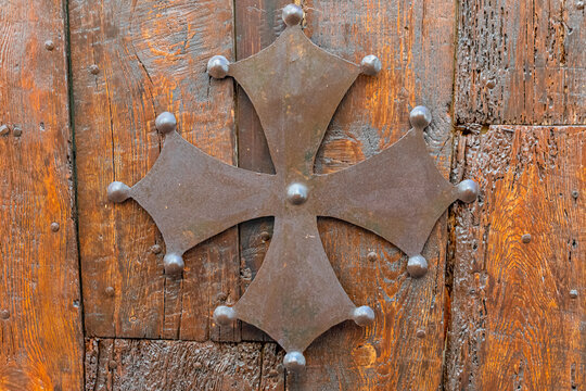 Croix en métal de l'Occitanie. Symbole de la région Occitanie-Pyrénées-Méditerranée, en France. Croix occitane sur fond de bois.