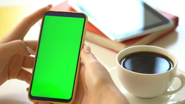 business woman using smartphone viewing green screen on mobile phone browsing chroma key online watching enjoying drinking coffee reading social media close up hands