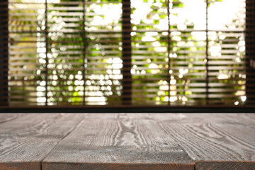 Wooden table and blurred window with blinds on background