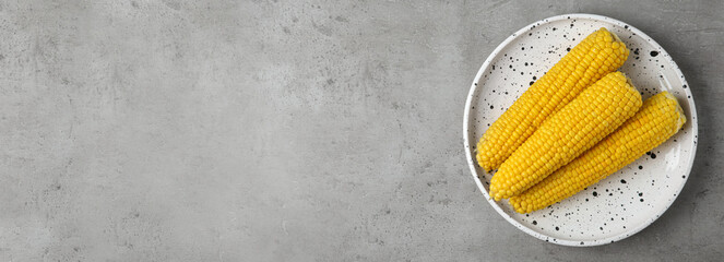 Tasty boiled corn cobs and space for text on light grey table, top view. Banner design