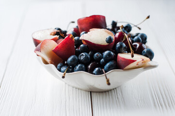Fruit salad with strawberry, blueberry, sweet cherry on wooden white background. Flat lay, top view