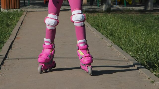 Close-up of Little Girl in Protection Pads Learning Roller Skating in a City Park. Childhood, Summer Activities and Healthy Lifestyle Concept
