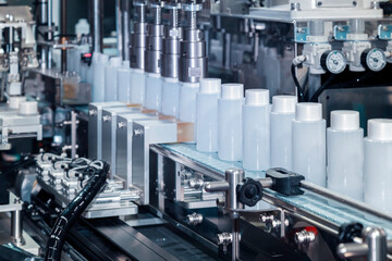 white plastic bottle moving on conveyor belt of auto capping and labeling machine at cosmetic and skin care manufacturing. cosmetic industry and ai technology machinery concept.