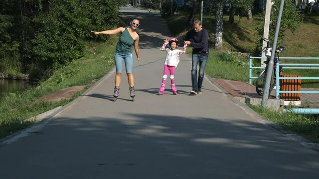 Family of Three Roller Skating in a Summer Park. Little Girl with Mom and Dad Enjoying Time Together. Happy Childhood, Summer Family Activities and Healthy Lifestyle Concept