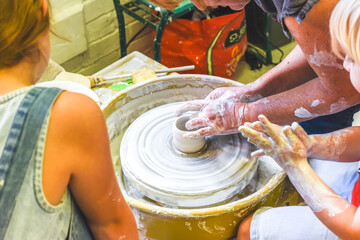 Children learning to make pottery as a hobby with their grandmother in a ceramics workshop