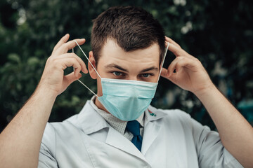 Doctor wearing protection blue face mask to prevent from corona virus, looking at the camera. Chief physician putting on preventive gear to save life. Stop epidemic diseases.