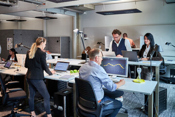Male and female entrepreneurs working at desks in illuminated creative office