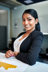 Portrait of smiling young female design professional at desk working in creative office