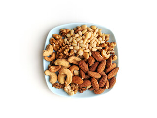 Small plate of assorted nuts with walnuts, cashew, almonds and pine nuts, on a light blue coffee coaster on white background