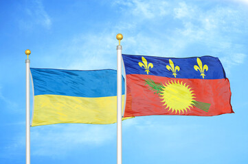 Ukraine and Guadeloupe two flags on flagpoles and blue sky