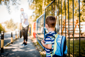 Business father and son going to kindergarten. They are wearing a medical face masks.