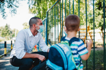 Business father and son going to kindergarten. They are wearing a medical face masks.