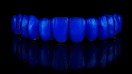 full wax up on titanium bar with blue wax teeth of the upper jaw on a black background © Dental Pro Content