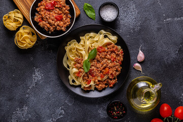 Traditional italian pasta bolognese on a black plate.