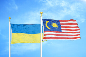 Ukraine and Malaysia two flags on flagpoles and blue sky